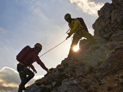 登山者帮助朋友爬上岩石坡。