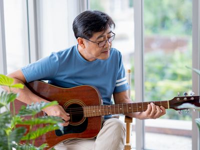 一个人坐在干净、光线充足的房间里弹着吉他。
