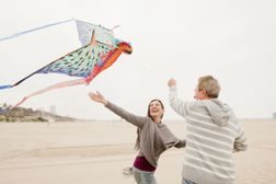 一对中年男女在海滩上放彩色风筝＂width=